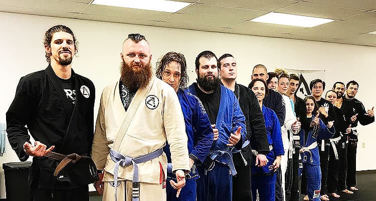 Students of Island Jiu-Jitsu Michigan lined up on the mats in their gis, throwing shakas