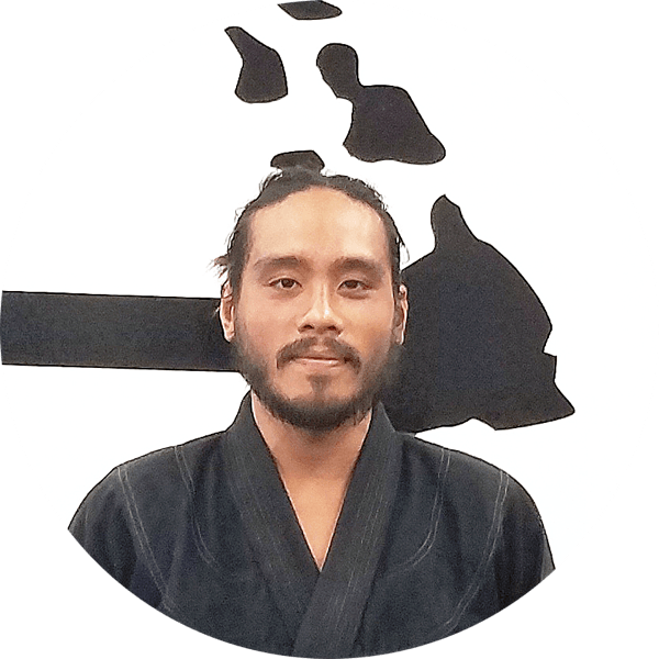 Archie in a black gi in front of the Island Jiu-Jitsu logo wall